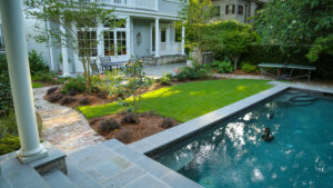 Swimming pool, lawn, brick paths, and layered planting in a Garden District landscape design
