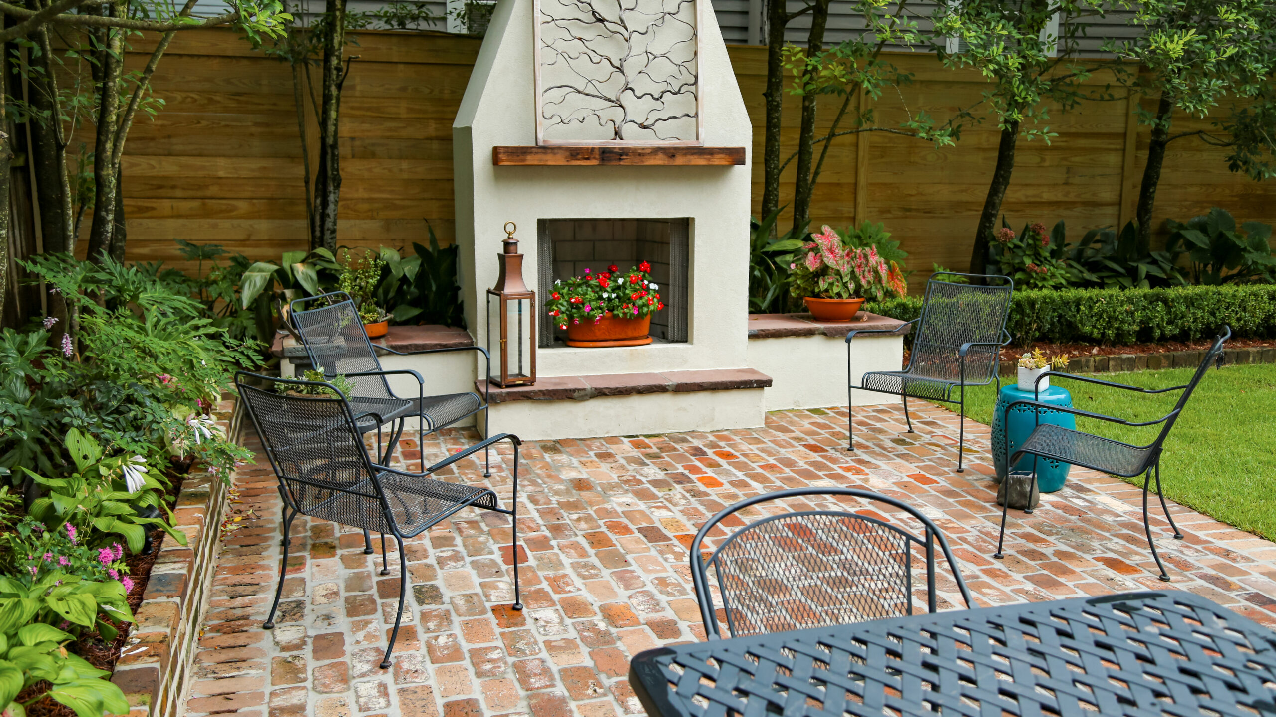 Outdoor fireplace and seating on a weathered brick patio in an Uptown New Orleans garden