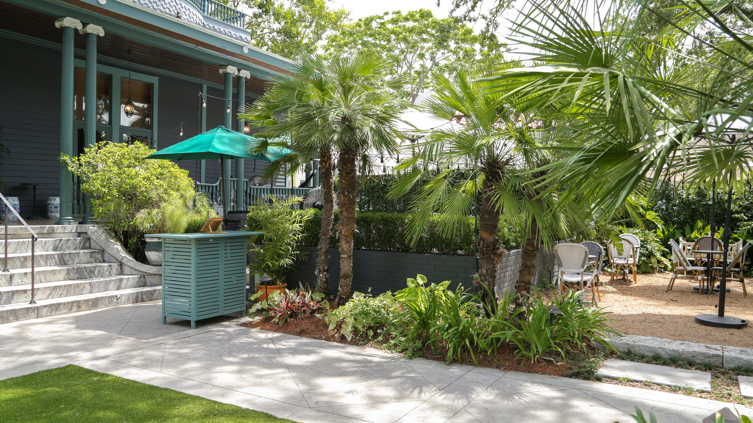 Palms and layered tropical planting beside a paved courtyard at The Chloe hotel in New Orleans