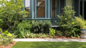 Layered shrubs and seasonal flowers along The Chloe’s historic mansion in Uptown New Orleans