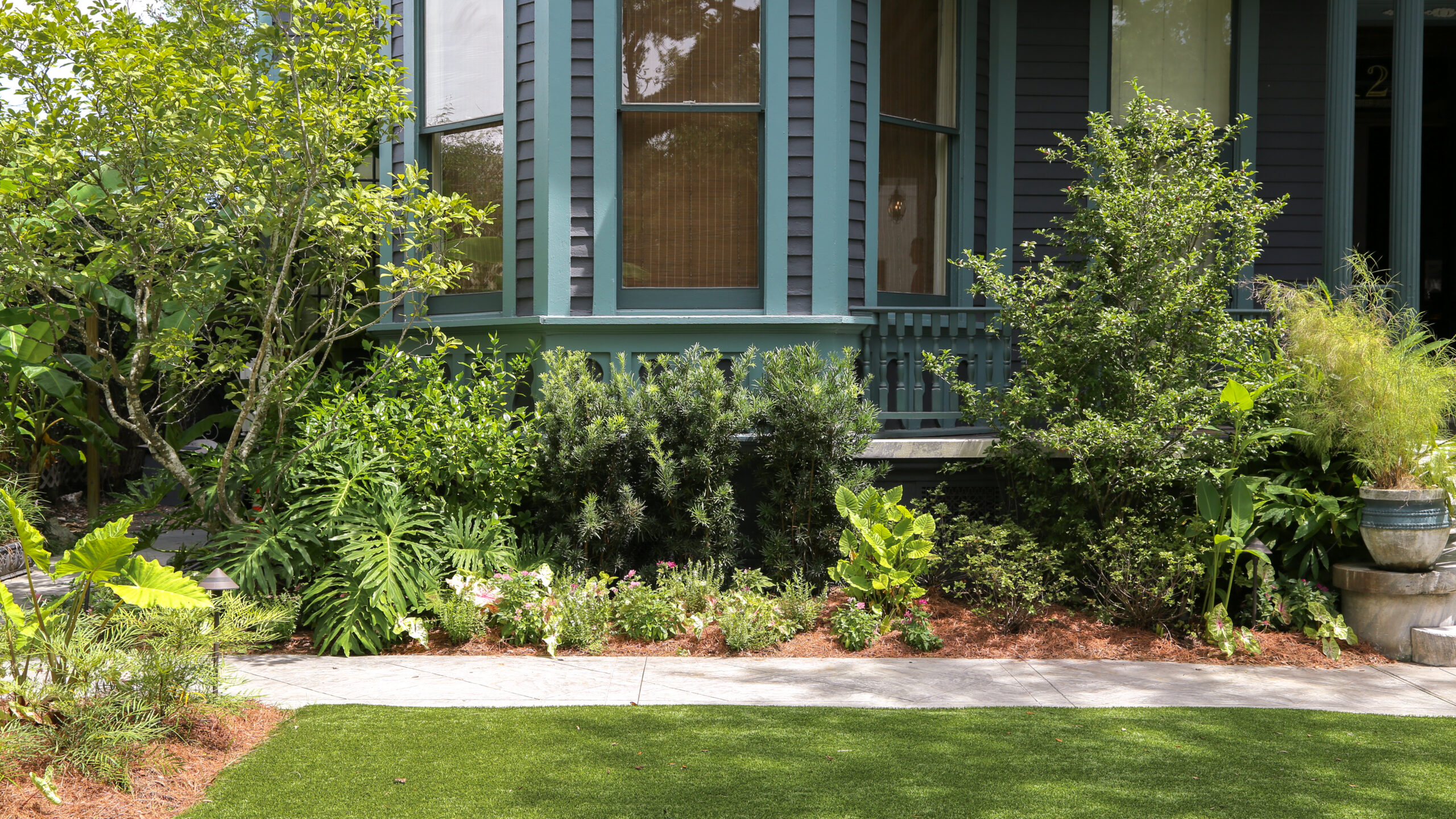 Layered shrubs and seasonal flowers along The Chloe’s historic mansion in Uptown New Orleans