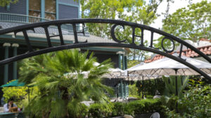 The Chloe iron hotel sign framed by palms and tropical foliage in Uptown New Orleans