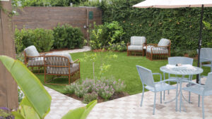 Outdoor lounge seating beside lawn and flowering beds in The Chloe’s New Orleans hotel garden