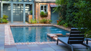 Brick-edged swimming pool and landscaped terrace in a completed backyard renovation in Old Metairie