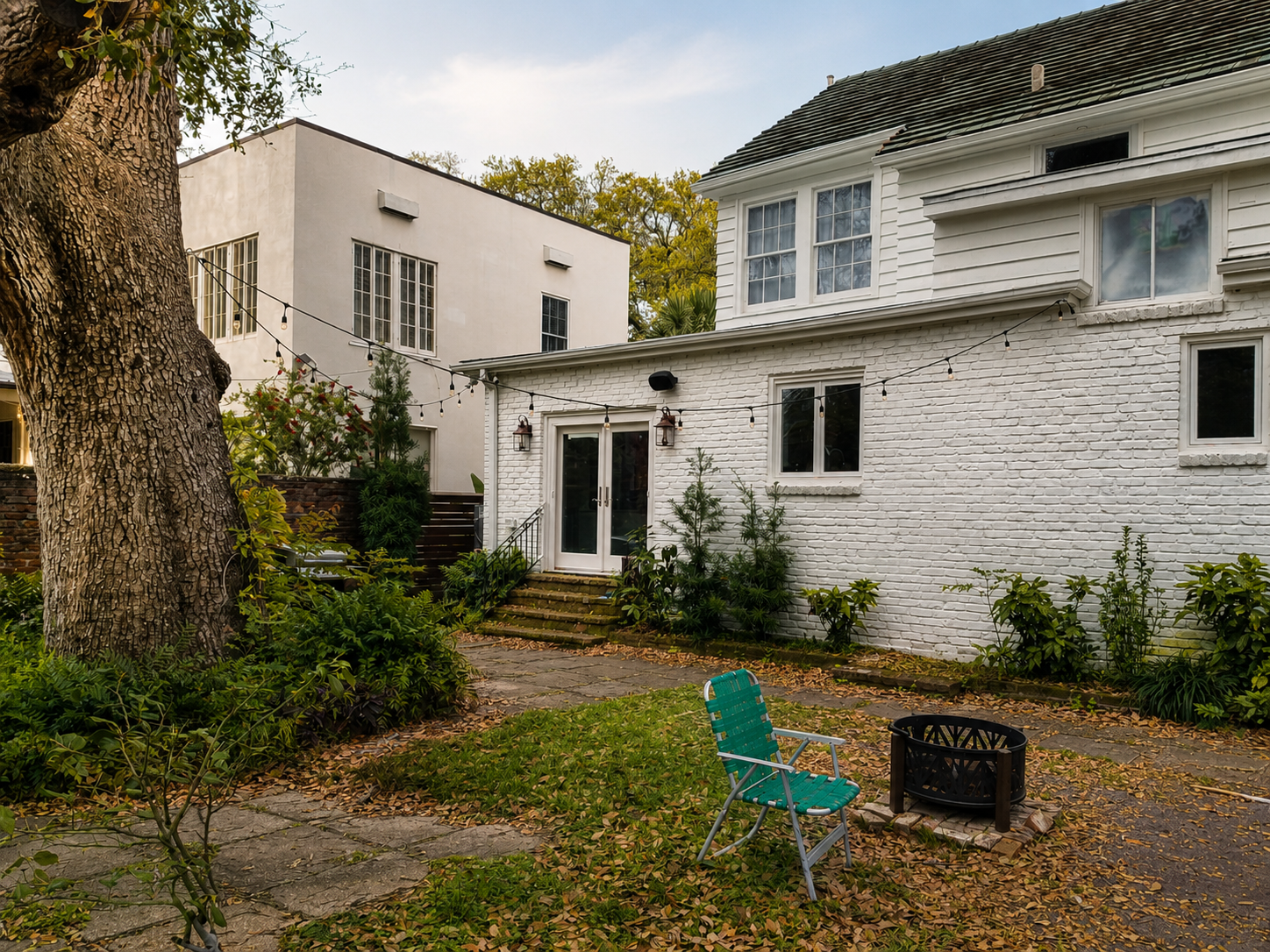 Audubon Boulevard rear garden before the landscape design-build, with patchy lawn, worn paths, and scattered planting beneath a live oak.