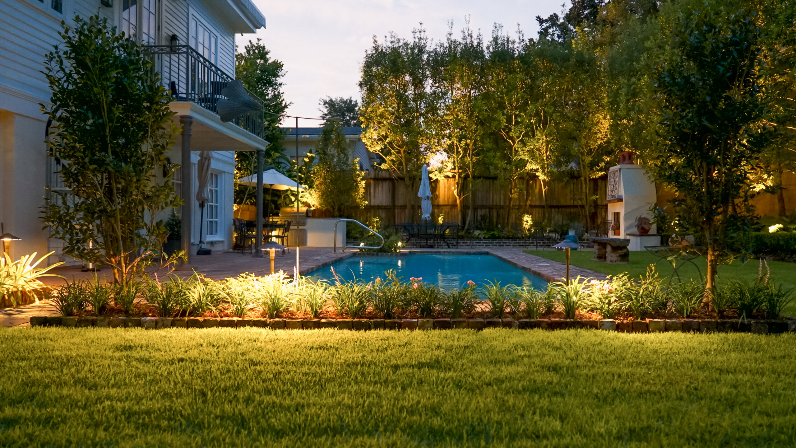 Illuminated swimming pool and garden at dusk in an Uptown New Orleans landscape