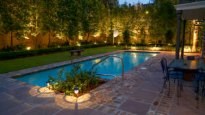 Swimming pool and brick terrace illuminated by low-voltage landscape lighting in an Uptown New Orleans garden