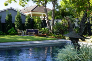 Contemporary swimming pool framed by palms and layered planting in an Uptown New Orleans garden