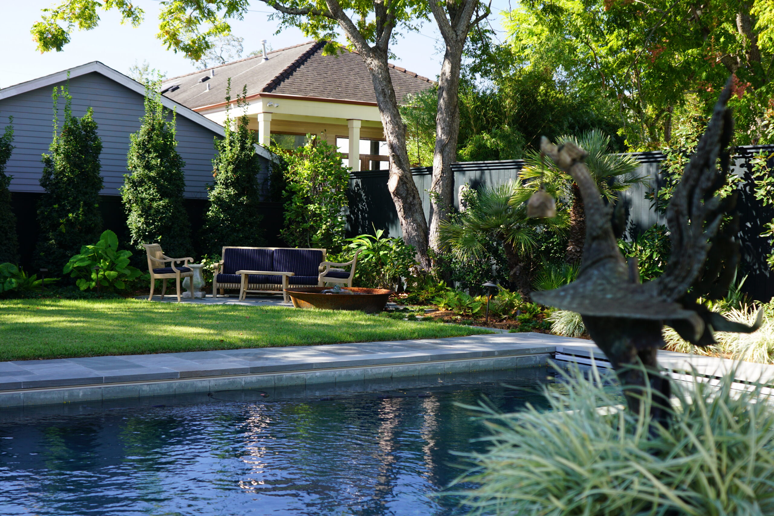 Contemporary swimming pool framed by palms and layered planting in an Uptown New Orleans garden