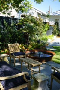 Outdoor seating beside a round water feature in a modern Uptown New Orleans garden
