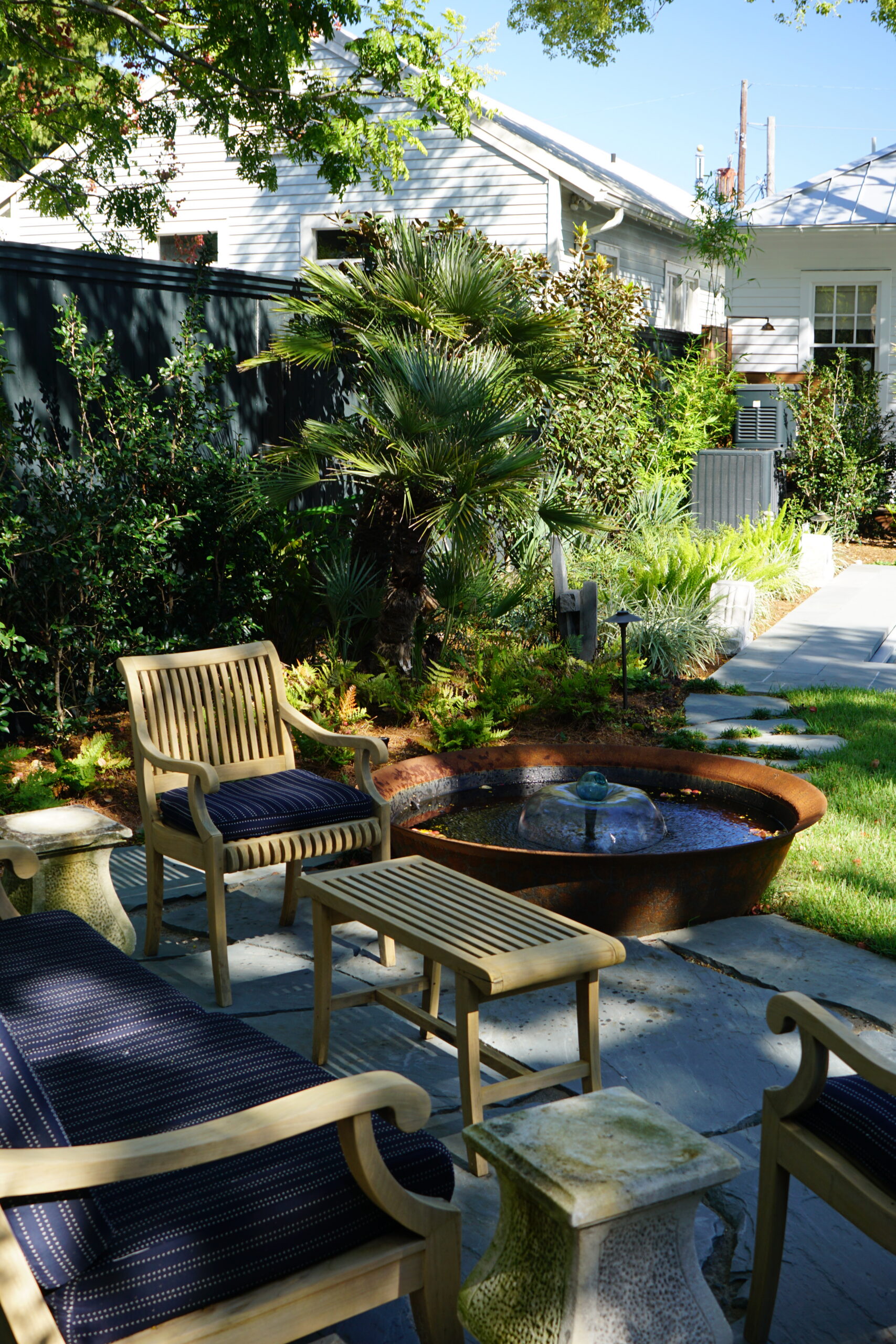 Outdoor seating beside a round water feature in a modern Uptown New Orleans garden