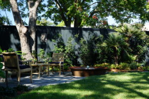 Zoysia lawn, water feature, and shaded seating within a modern Uptown New Orleans pool garden