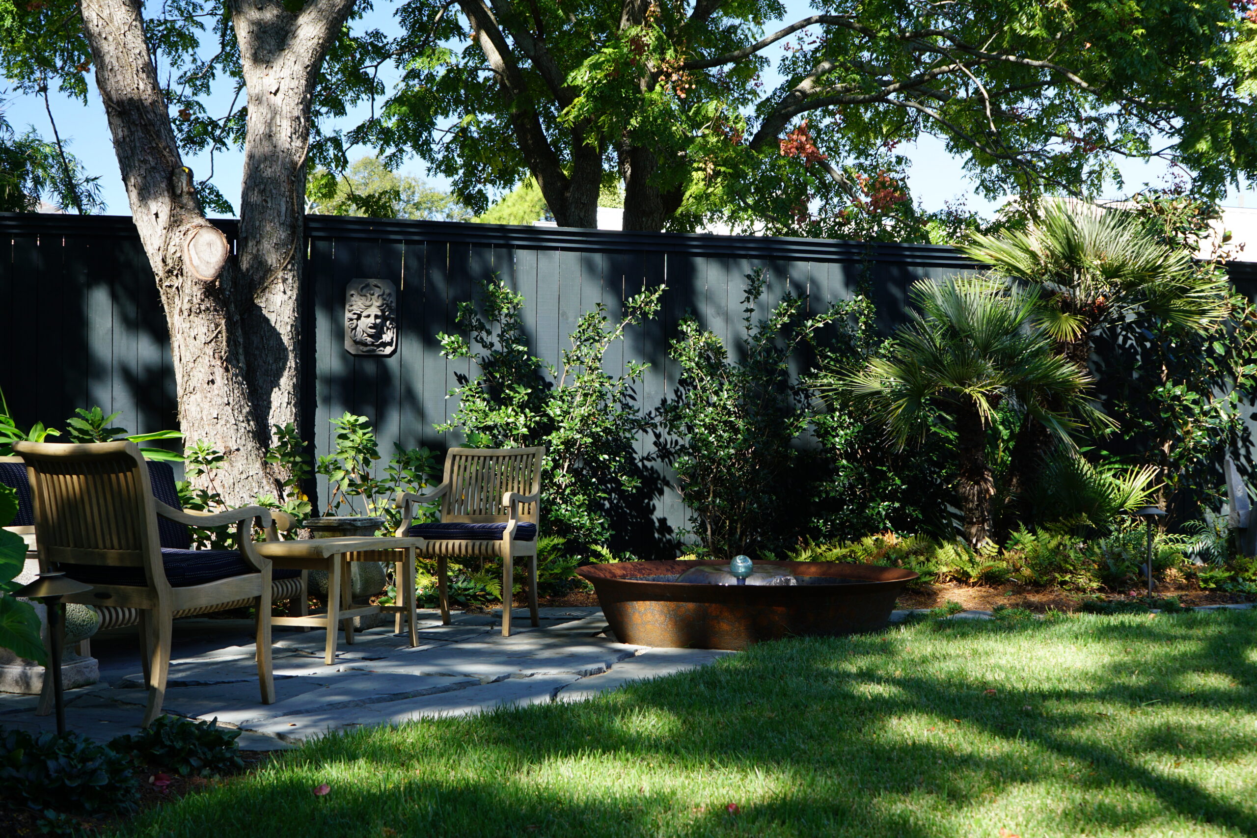 Zoysia lawn, water feature, and shaded seating within a modern Uptown New Orleans pool garden