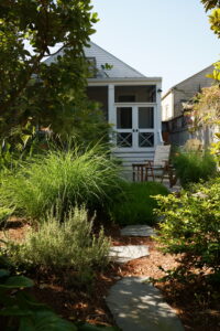 Stepping-stone path through mature ornamental grasses and layered planting toward an Uptown New Orleans porch