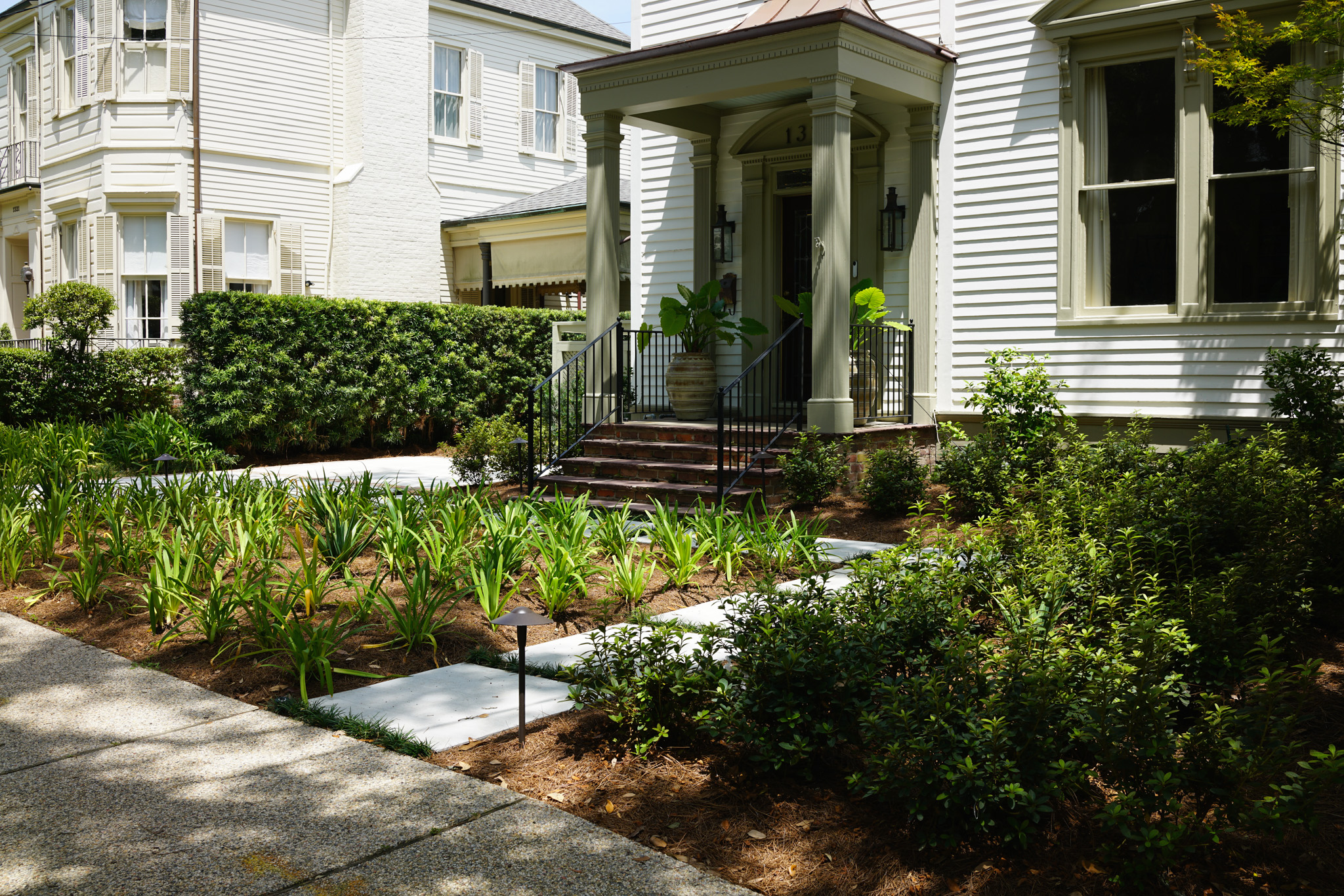 Traditional Uptown New Orleans front garden with layered evergreen plantings, agapanthus, and a Japanese maple at a State Street residence.