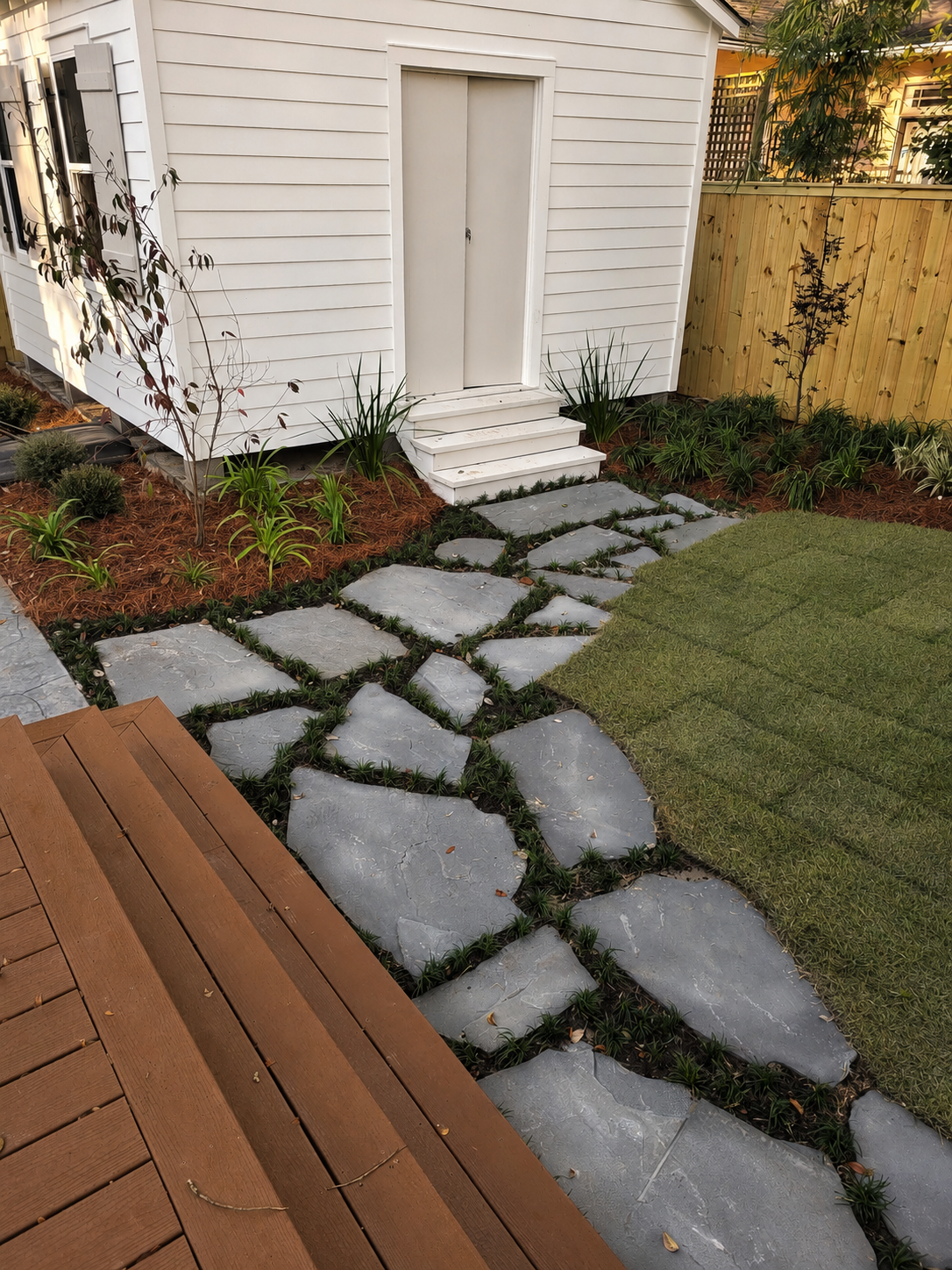 Irregular flagstone path with planted joints connecting the wooden deck and garden shed at the Audubon Boulevard garden.