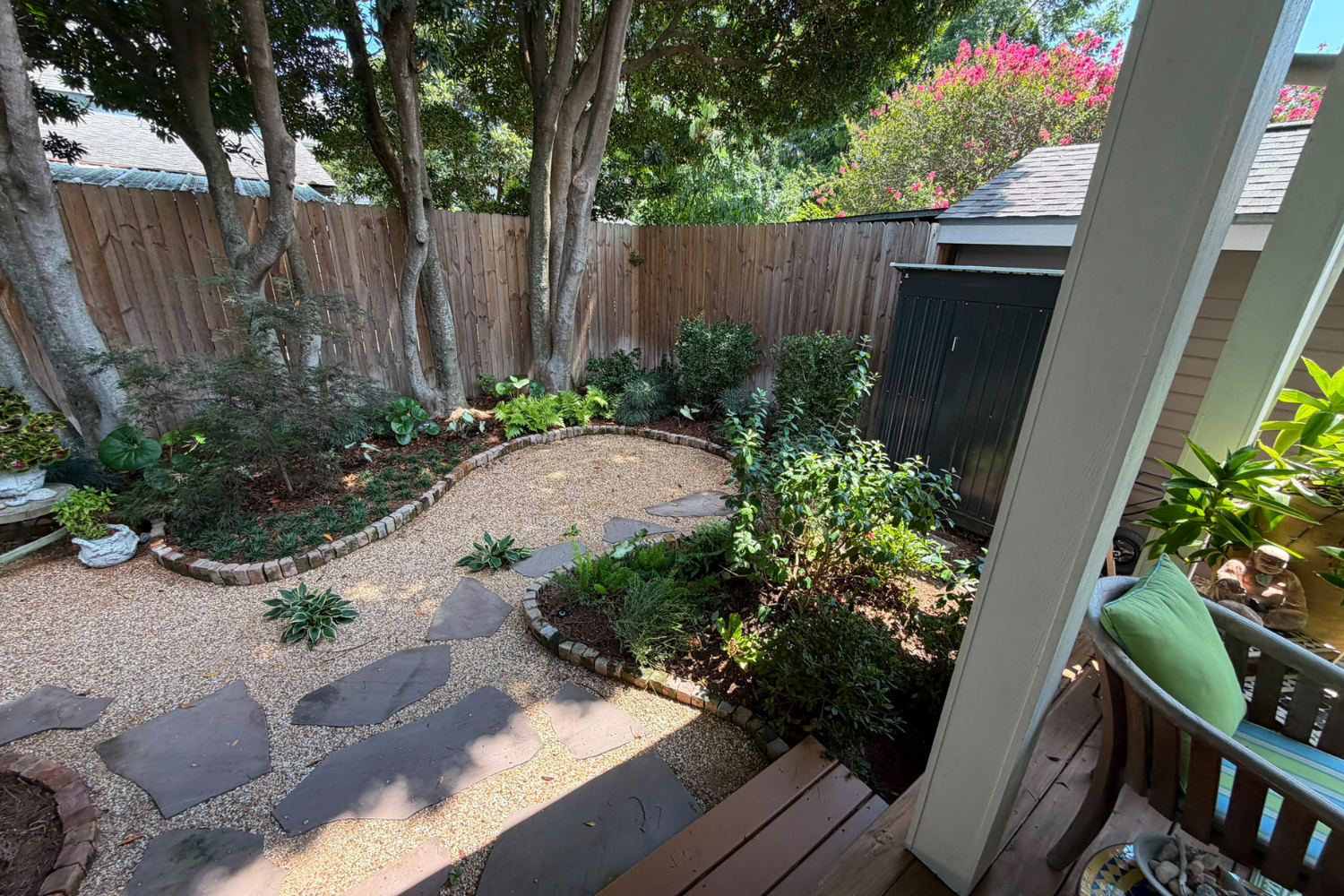 Curved crushed brownstone path with flagstone steppers, brick-edged planting beds, and mature trees at the Constance Street Garden in Uptown New Orleans