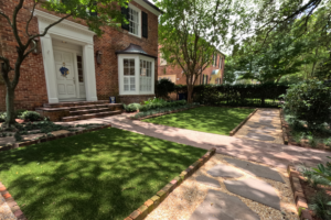 Nashville Avenue Garden in Uptown New Orleans with brick edging, flagstone steppers, lawn panels, and shaded planting at a traditional brick home.