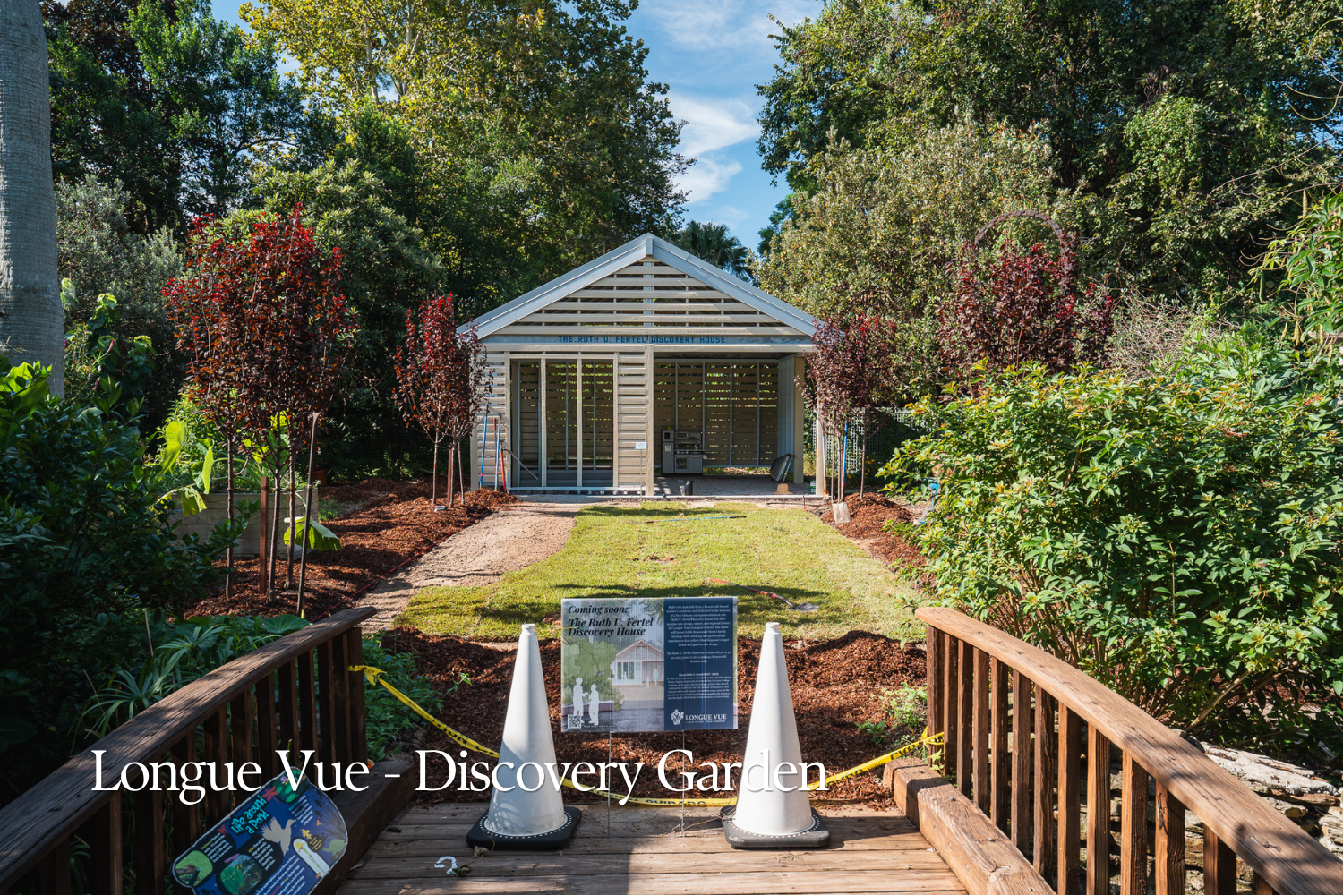 Entrance to the Longue Vue Discovery Garden in New Orleans, with young ornamental trees, lawn, and planting beds leading to the Ruth U. Fertel Discovery House.