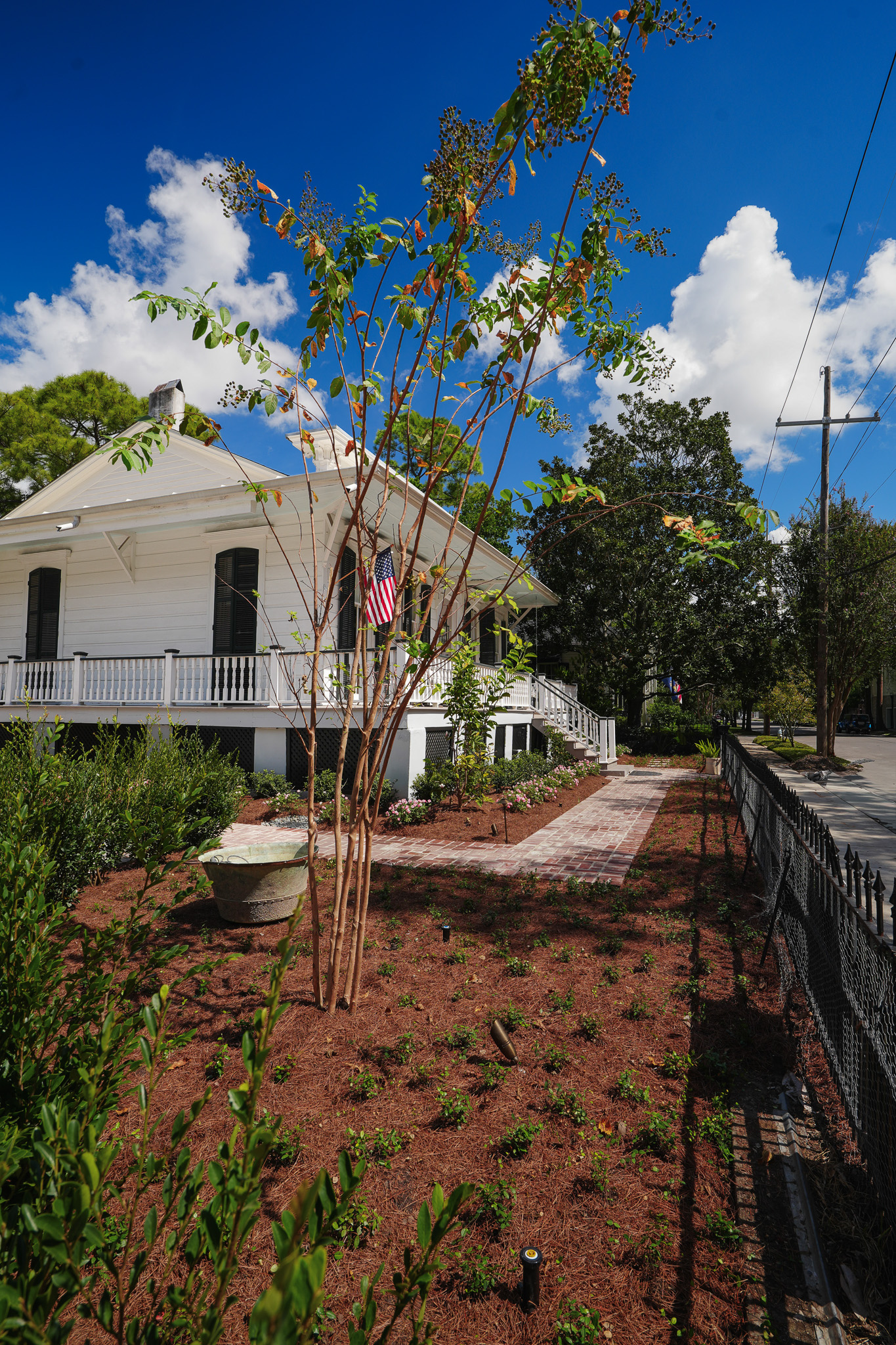 Historic New Orleans home with brick walkways, flowering shrubs, and newly installed front-garden planting.