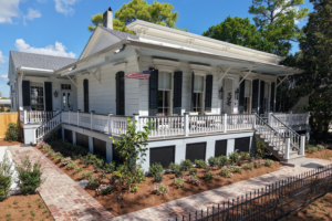 Restored New Orleans home with a wraparound porch, brick walkways, and newly installed front-garden planting.